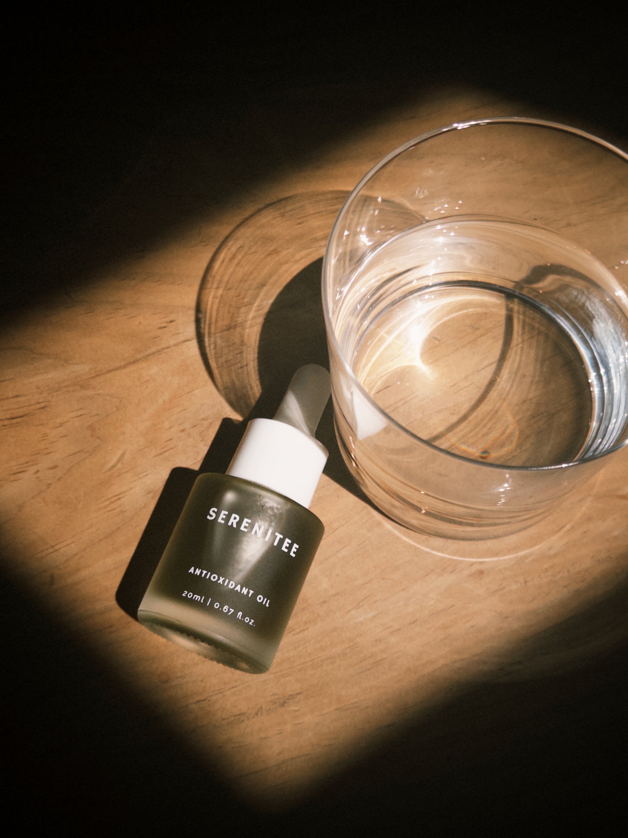 Serenitee Blue Tansy Antioxidant Oil glass bottle on a vanity, showcasing clean beauty packaging for a 100% waterless and preservative-free formula.